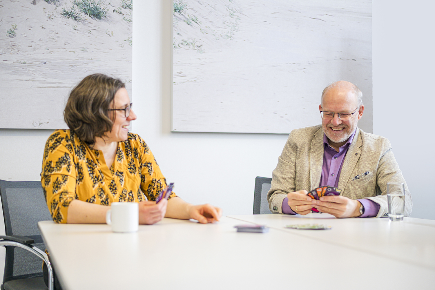 Two colleagues participating in a Scrum Poker session to estimate project tasks at a white table.