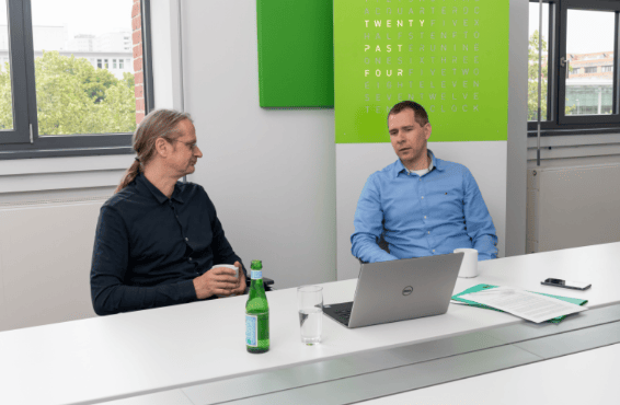 A photo of entimo's COO and CEO in discussion at a conference table.