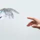 Robotic hand and human hand reaching toward each other – AI in statistical programming