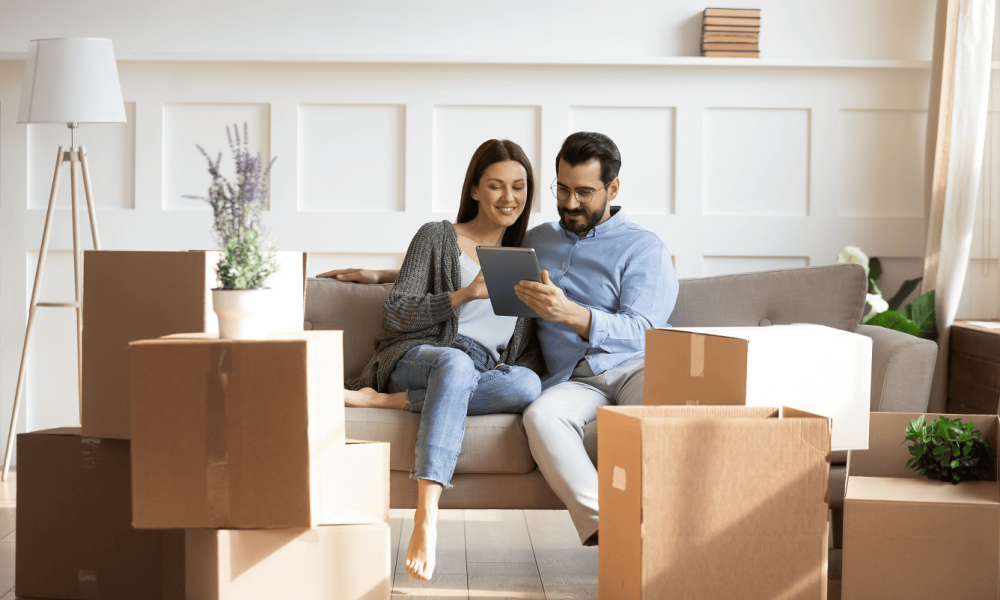 Happy couple on a sofa among moving boxes – symbol of entimICE FastTrack and Posit as the ideal couple for R in clinical research
